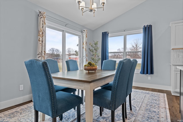 dining room with lofted ceiling, baseboards, wood finished floors, and a notable chandelier