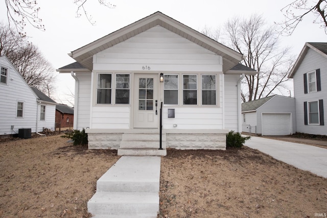 bungalow-style home with a garage, driveway, central AC, and an outbuilding