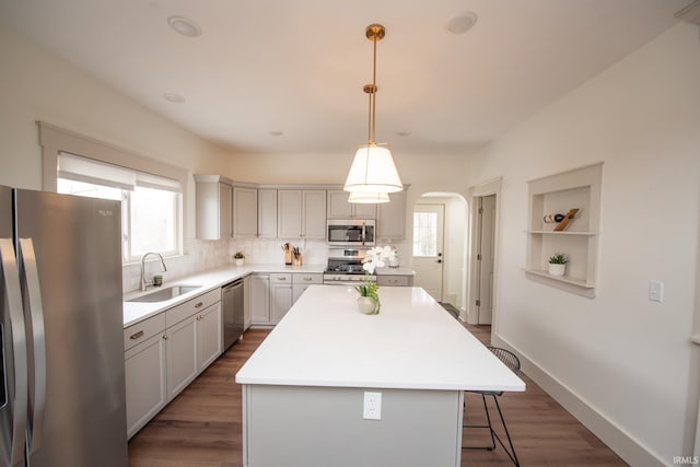 kitchen featuring dark wood-style flooring, appliances with stainless steel finishes, arched walkways, and a sink