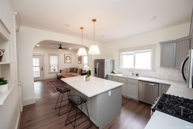 kitchen with arched walkways, appliances with stainless steel finishes, gray cabinets, and a sink