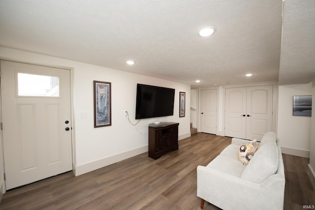 living area with a textured ceiling, baseboards, wood finished floors, and recessed lighting