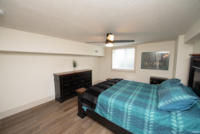 bedroom with a textured ceiling, ceiling fan, wood finished floors, and baseboards