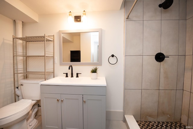 bathroom featuring toilet, a tile shower, and vanity