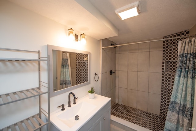 full bathroom featuring tiled shower and vanity