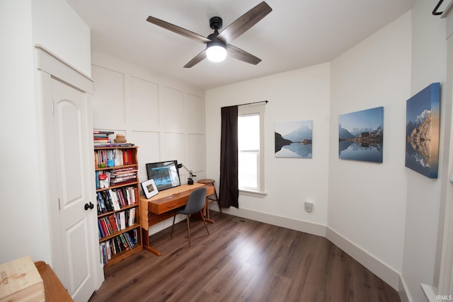 office space with baseboards, a ceiling fan, a decorative wall, and wood finished floors