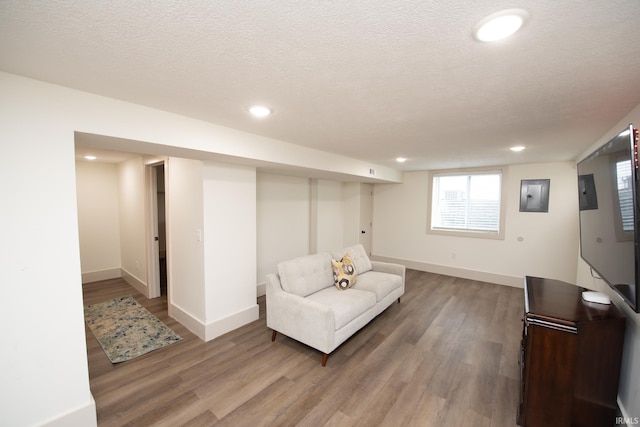 living area featuring light wood-type flooring, baseboards, a textured ceiling, and recessed lighting