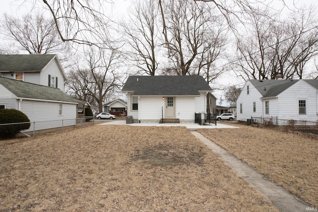 view of front facade featuring entry steps, a shingled roof, and fence