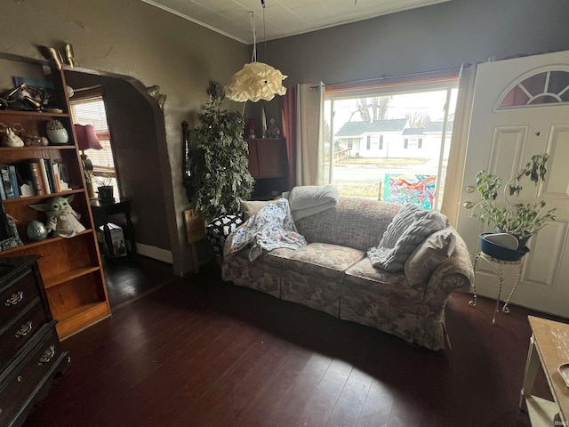 living area featuring arched walkways and dark wood-type flooring