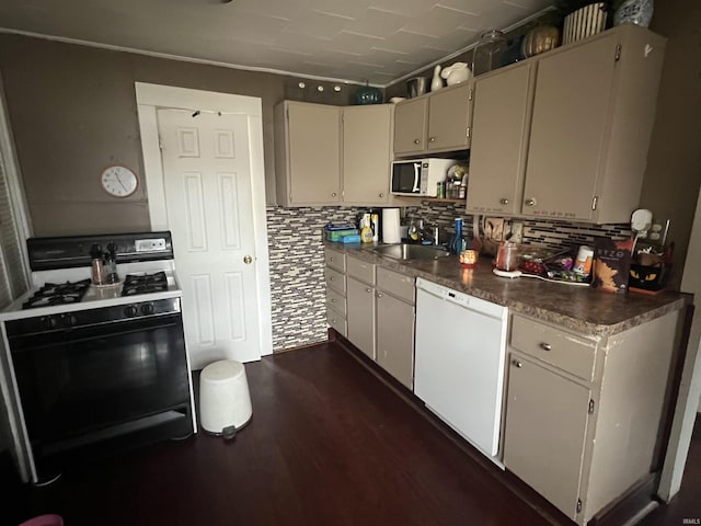 kitchen featuring dark wood finished floors, dark countertops, decorative backsplash, a sink, and white appliances