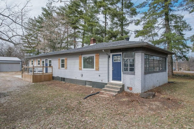 view of front of home with entry steps, a shingled roof, brick siding, an outdoor structure, and a chimney