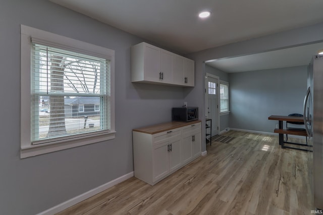 kitchen featuring stainless steel appliances, white cabinets, light wood-style floors, and baseboards