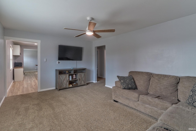 living area with carpet flooring, a ceiling fan, and baseboards