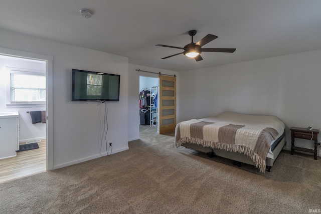 unfurnished bedroom with a barn door, baseboards, ensuite bathroom, a spacious closet, and carpet flooring