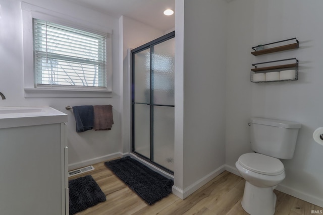 bathroom with toilet, wood finished floors, visible vents, baseboards, and a stall shower