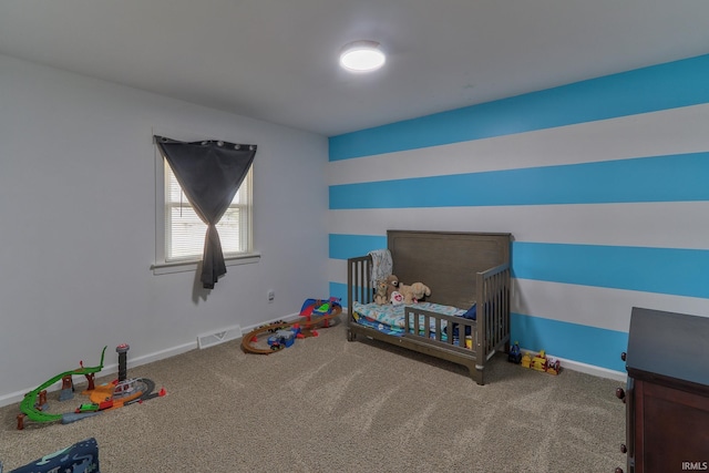 carpeted bedroom with a crib, visible vents, and baseboards