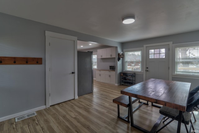 dining room featuring baseboards, a healthy amount of sunlight, visible vents, and light wood-style floors