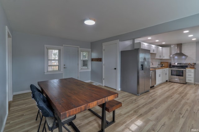 dining room featuring light wood-style floors, baseboards, and recessed lighting