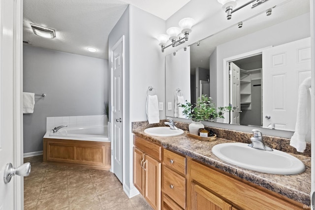 full bathroom featuring a textured ceiling, double vanity, tile patterned flooring, and a sink