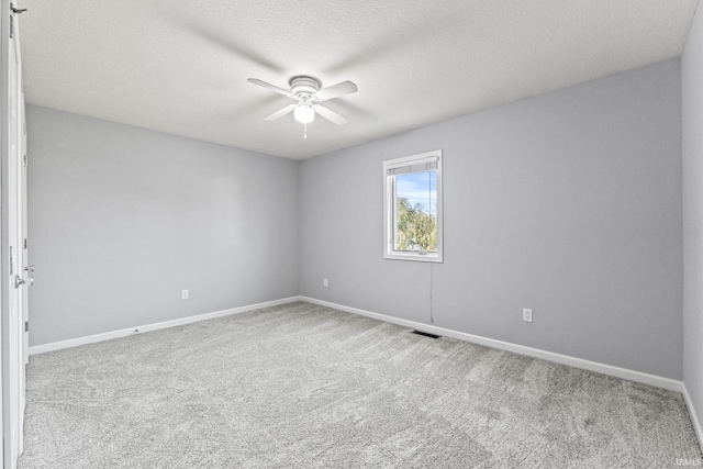 carpeted spare room featuring a ceiling fan, a textured ceiling, and baseboards