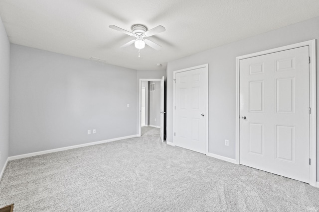 unfurnished bedroom featuring carpet, a textured ceiling, baseboards, and a ceiling fan