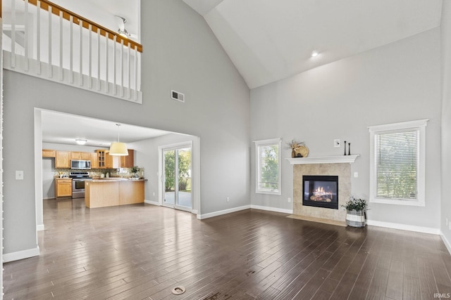 unfurnished living room featuring dark wood-style floors, a tile fireplace, lofted ceiling, and baseboards