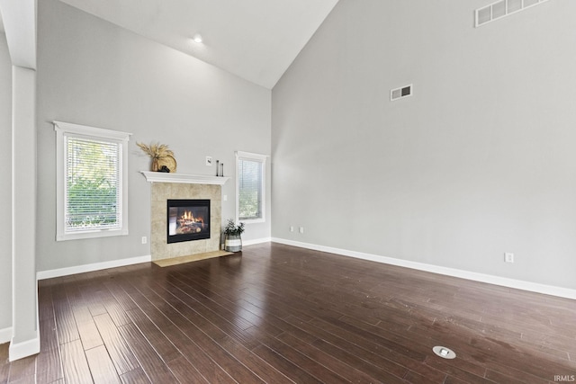 unfurnished living room with a wealth of natural light, a tile fireplace, wood finished floors, and visible vents