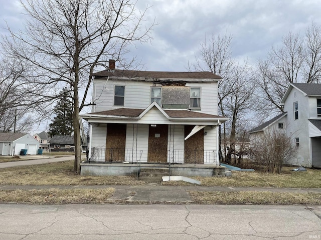 view of front facade featuring covered porch, a shingled roof, and a chimney