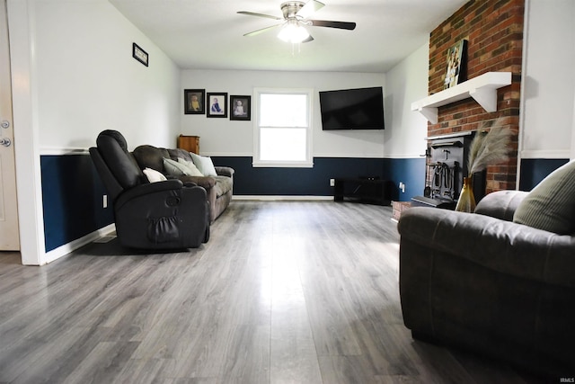 living area featuring baseboards, a fireplace, a ceiling fan, and wood finished floors