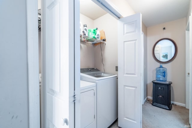 clothes washing area featuring light carpet, laundry area, baseboards, and separate washer and dryer