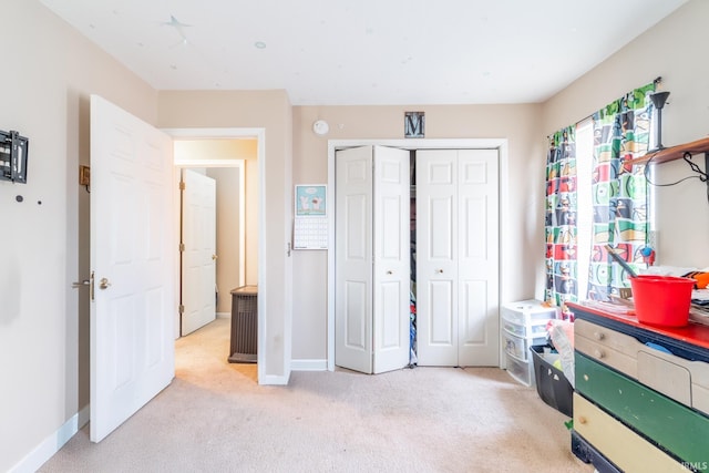 bedroom with baseboards, a closet, and light colored carpet