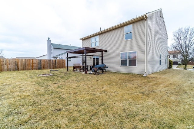 rear view of house with a yard, fence, and a fire pit