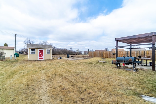 view of yard with fence, a storage unit, and an outbuilding