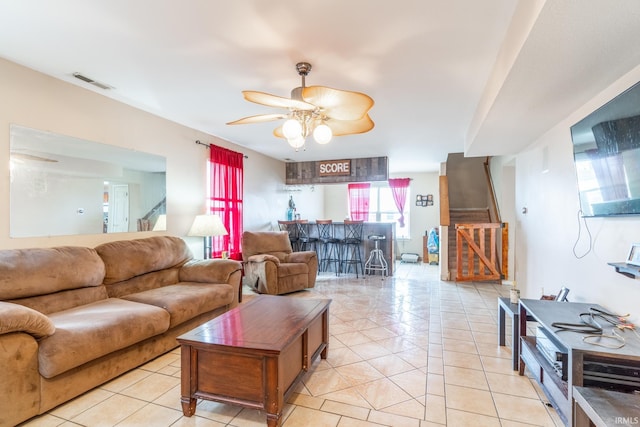 living room featuring a bar, stairway, light tile patterned floors, and visible vents