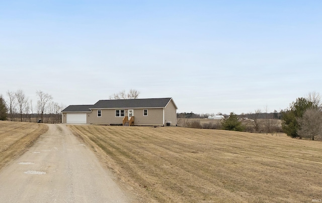 view of front facade featuring an attached garage, dirt driveway, and a front yard