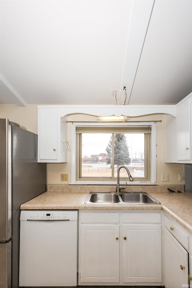 kitchen with light countertops, white cabinets, white dishwasher, and a sink