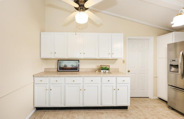 kitchen featuring light tile patterned floors, lofted ceiling, light countertops, white cabinetry, and stainless steel fridge