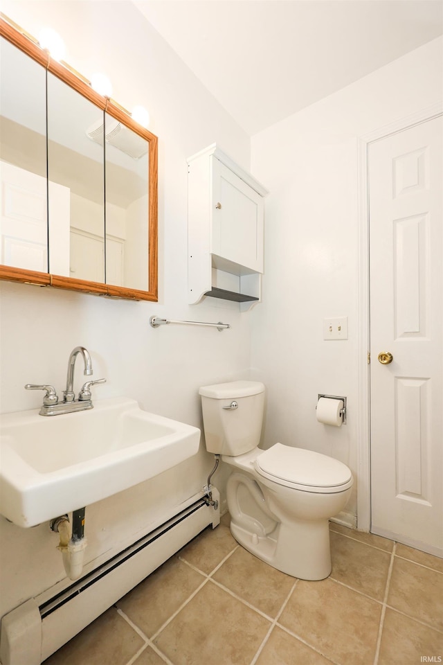 half bath with toilet, a baseboard radiator, tile patterned flooring, and a sink