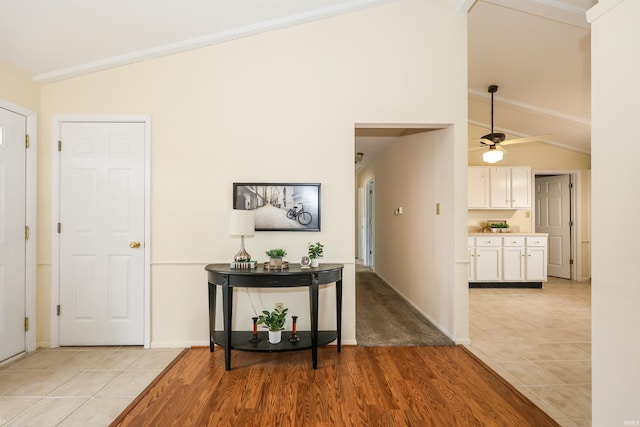 corridor with lofted ceiling, light tile patterned floors, and baseboards