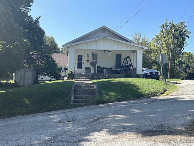 view of front facade with covered porch, board and batten siding, and a front yard