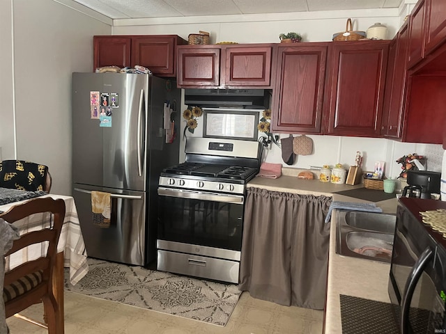 kitchen with reddish brown cabinets, extractor fan, and stainless steel appliances