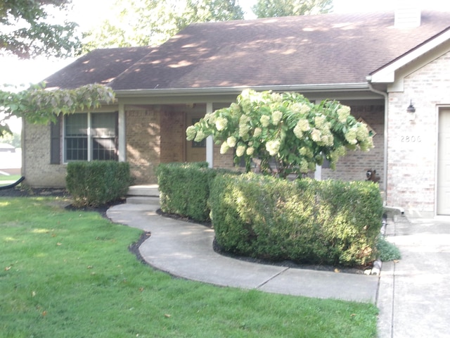 view of front of house featuring a garage, a front yard, brick siding, and roof with shingles