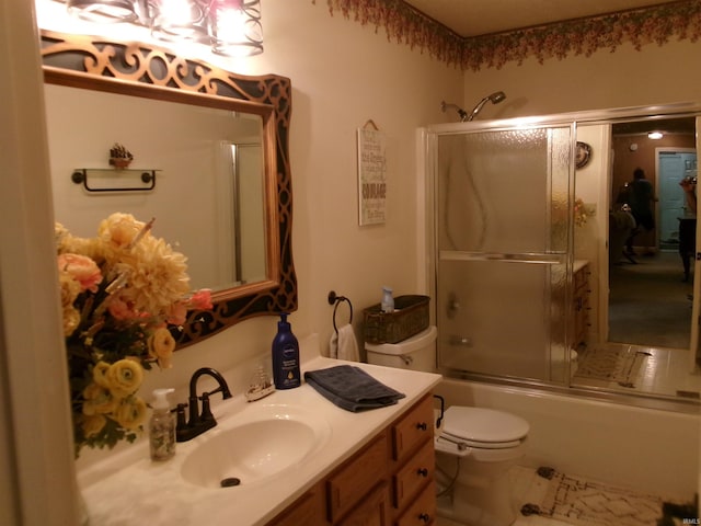 bathroom featuring combined bath / shower with glass door, vanity, and toilet