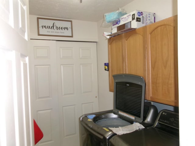 clothes washing area featuring separate washer and dryer and cabinet space