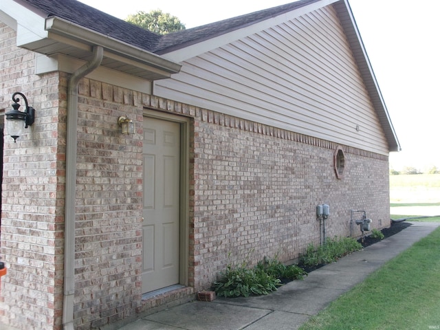 view of home's exterior featuring roof with shingles and brick siding