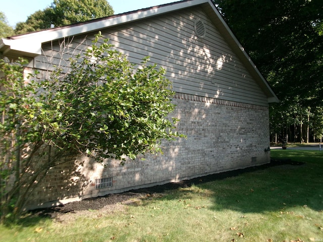 view of side of property featuring crawl space, brick siding, and a lawn