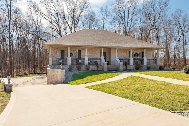 view of front of home with stone siding, a front lawn, a porch, and roof with shingles