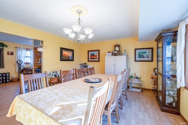 dining space featuring a chandelier, light wood-style flooring, and baseboards