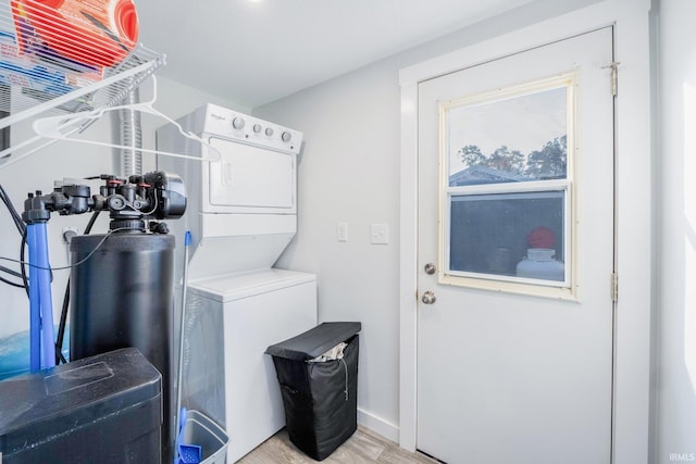 laundry room featuring light wood-type flooring, laundry area, and stacked washer / dryer