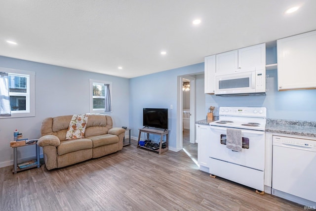 living room with light wood-style floors, recessed lighting, and baseboards