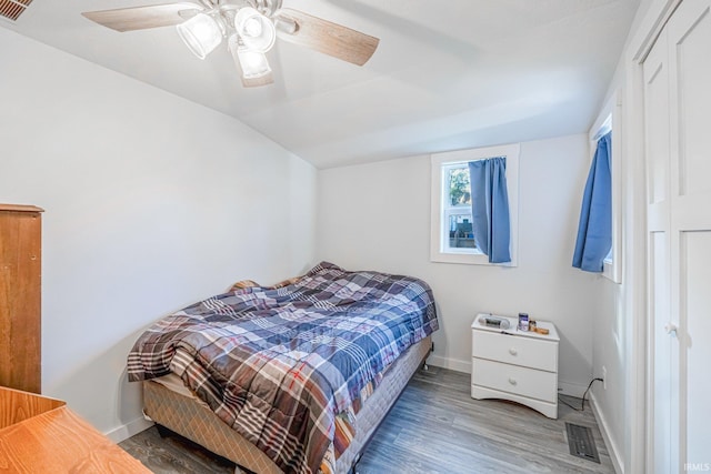 bedroom with visible vents, vaulted ceiling, baseboards, and wood finished floors